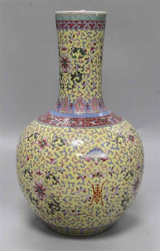A Canton enamelled bottle vase, decorated flowers, foliate scrolls and Chinese characters on a yellow ground, height 40cm, faults